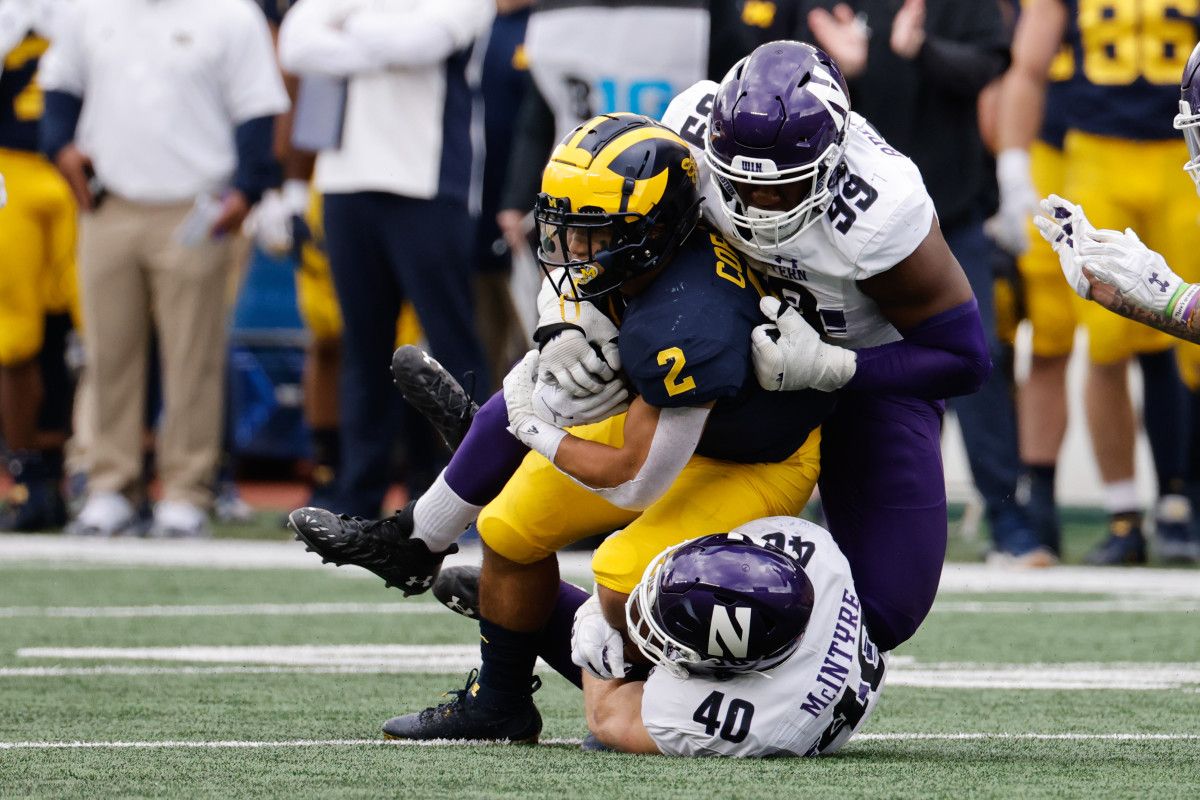 Michigan Wolverines running back Blake Corum (2) is tackled by Northwestern Wildcats linebacker Peter McIntyre (40) and defensive lineman Adetomiwa Adebawore (99) in the first half at Michigan Stadium.