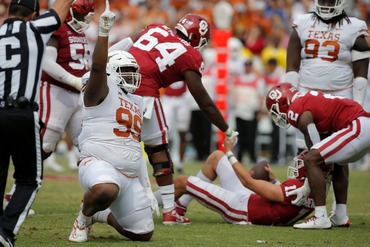 Texas defensive lineman Keondre Coburn (99) celebrates as Oklahoma quarterback Davis Beville (11) is helped up after a sack during the Longhorns' 49-0 win Saturday at the Cotton Bowl in Dallas. cover main