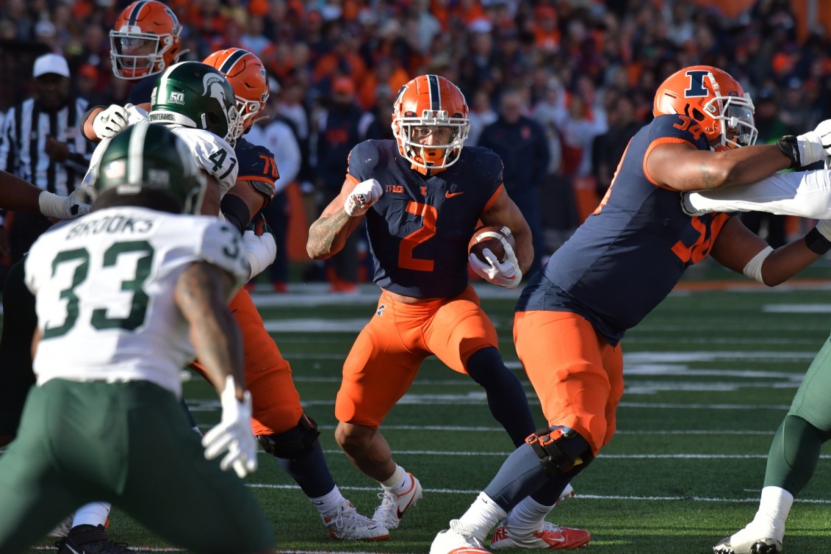 Illinois Fighting Illini running back Chase Brown (2) runs through an opening against the Michigan State Spartans. Mandatory Credit: Ron Johnson-USA TODAY