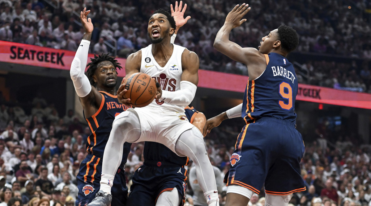 Cleveland Cavaliers' Donovan Mitchell, center, drives to the basket against New York Knicks' Julius Randle, left, and RJ Barrett during the first half of Game 1.