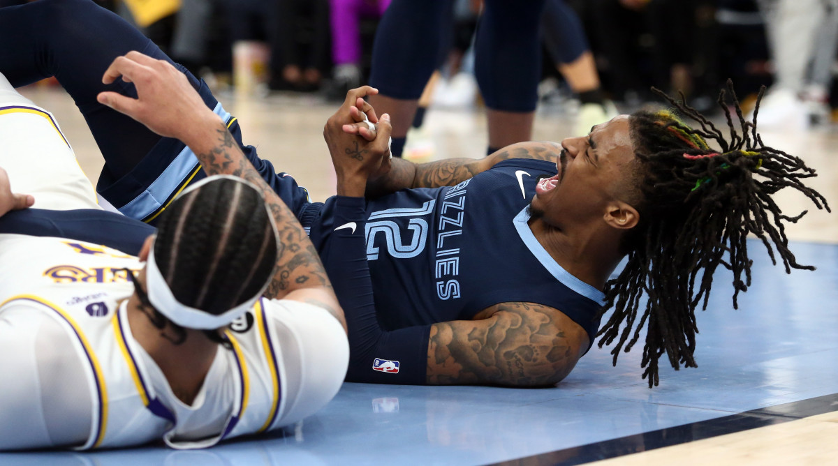 Ja Morant grabs his hand in pain after it was injured on a collision with Anthony Davis