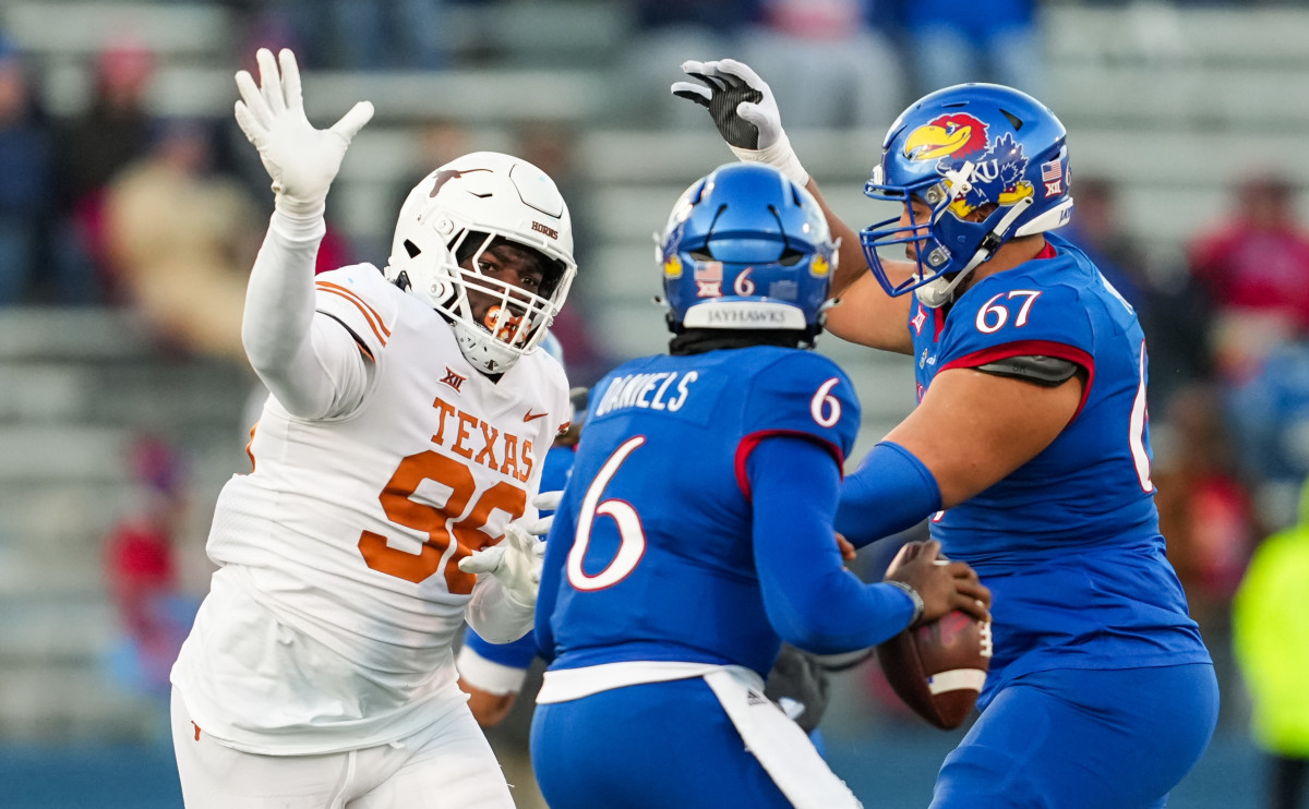 Nov 19, 2022; Lawrence, Kansas, USA; Texas Longhorns defensive lineman Moro Ojomo (98) rushes Kansas Jayhawks quarterback Jalon Daniels (6) as offensive lineman Dominick Puni (67) blocks during the second half at David Booth Kansas Memorial Stadium.