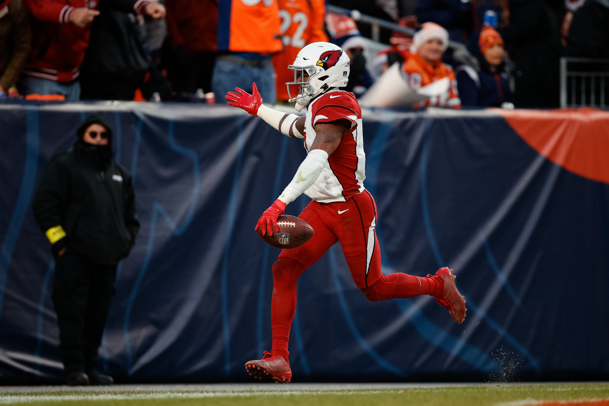 Cardinals safety Budda Baker runs with the ball in his hand, one hand raised toward the sky in celebration of an interception