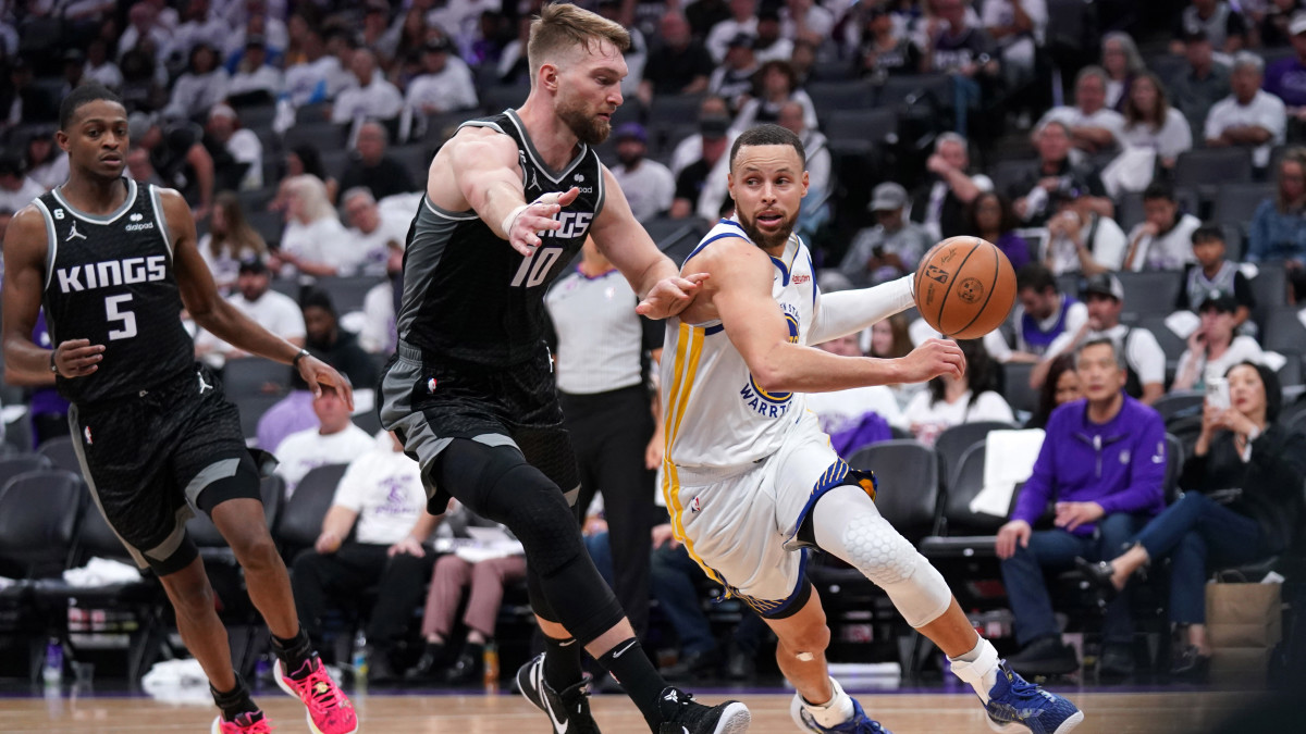 Golden State Warriors guard Stephen Curry dribbles past Sacramento Kings forward Domantas Sabonis.