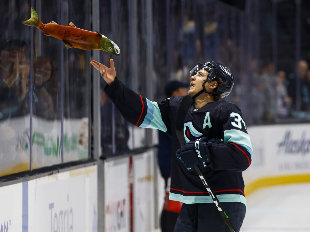 Seattle Kraken center Yanni Gourde (37) tosses a toy sockeye salmon to fans following a 4-0 victory against the Vancouver Canucks.