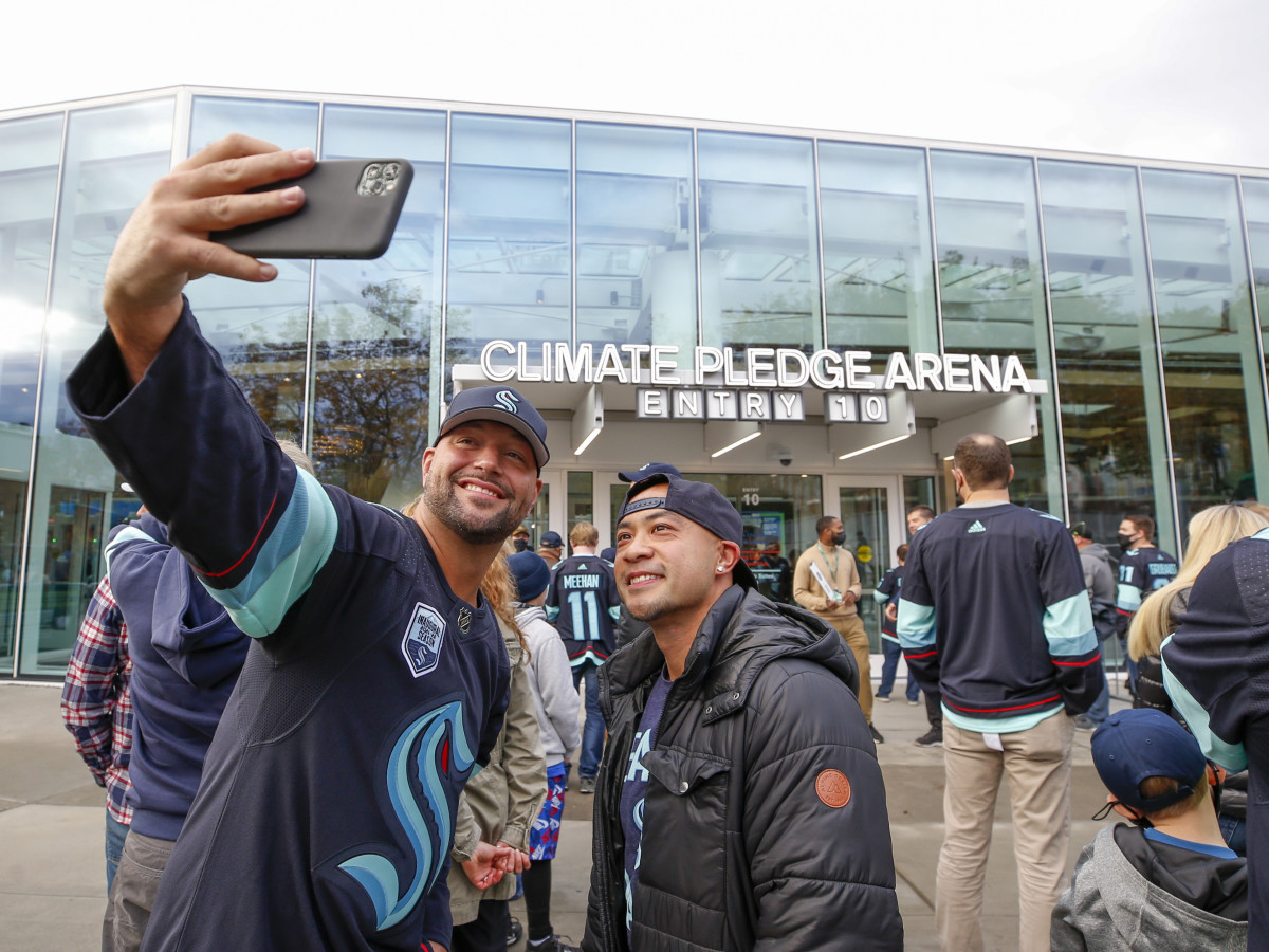 Seattle Kraken fans take a selfie outside Climate Pledge Arena before a game between the Kraken and the Vancouver Canucks.