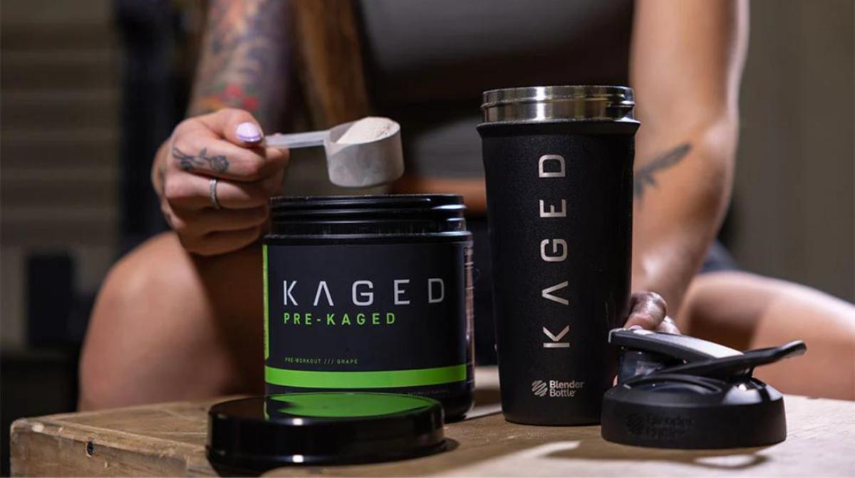 Woman scooping Kaged pre-workout powder into a shaker bottle