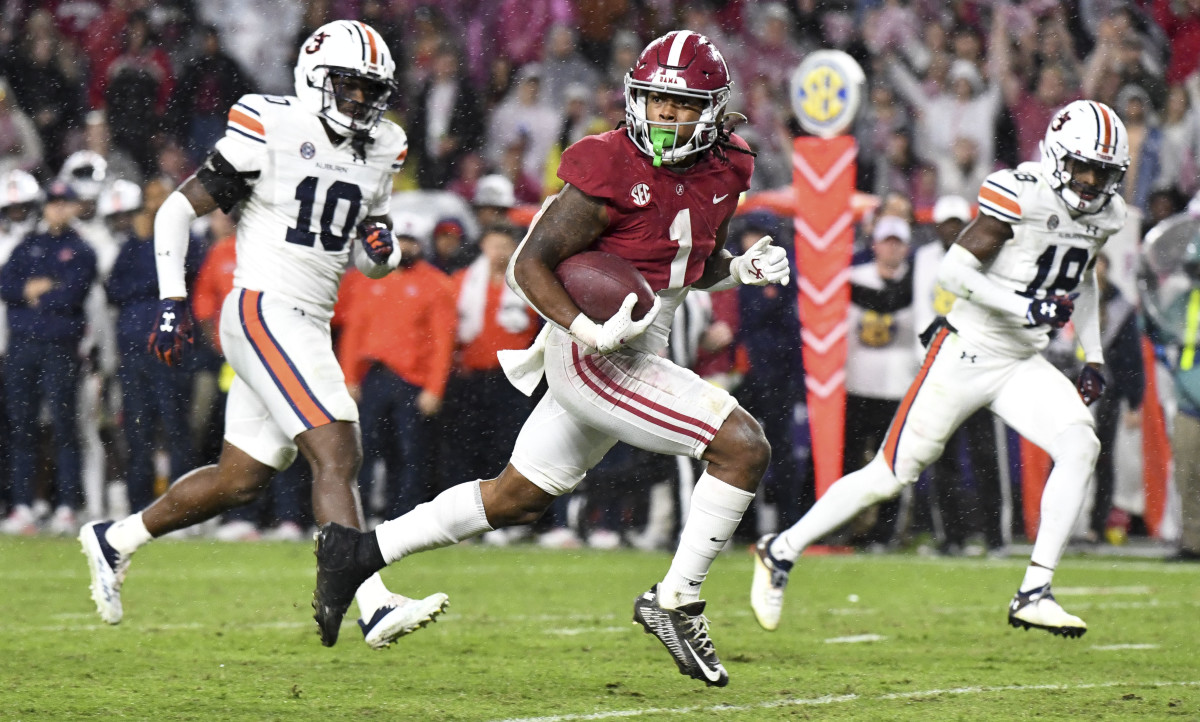 running back Jahmyr Gibbs runs holding the ball as two Auburn defenders try to catch him
