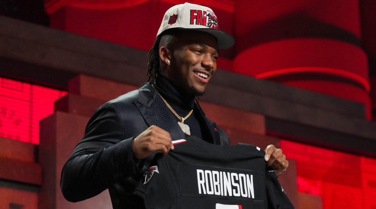 Bijan Robinson holds up his new Atlanta Falcons jersey after being drafted