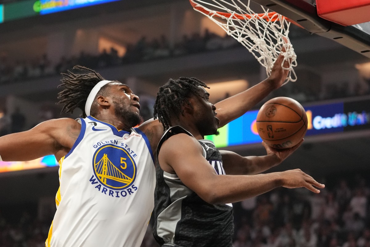 Sacramento Kings guard Davion Mitchell shoots the basketball while Golden State Warriors forward Kevon Looney jumps up to try to stop it