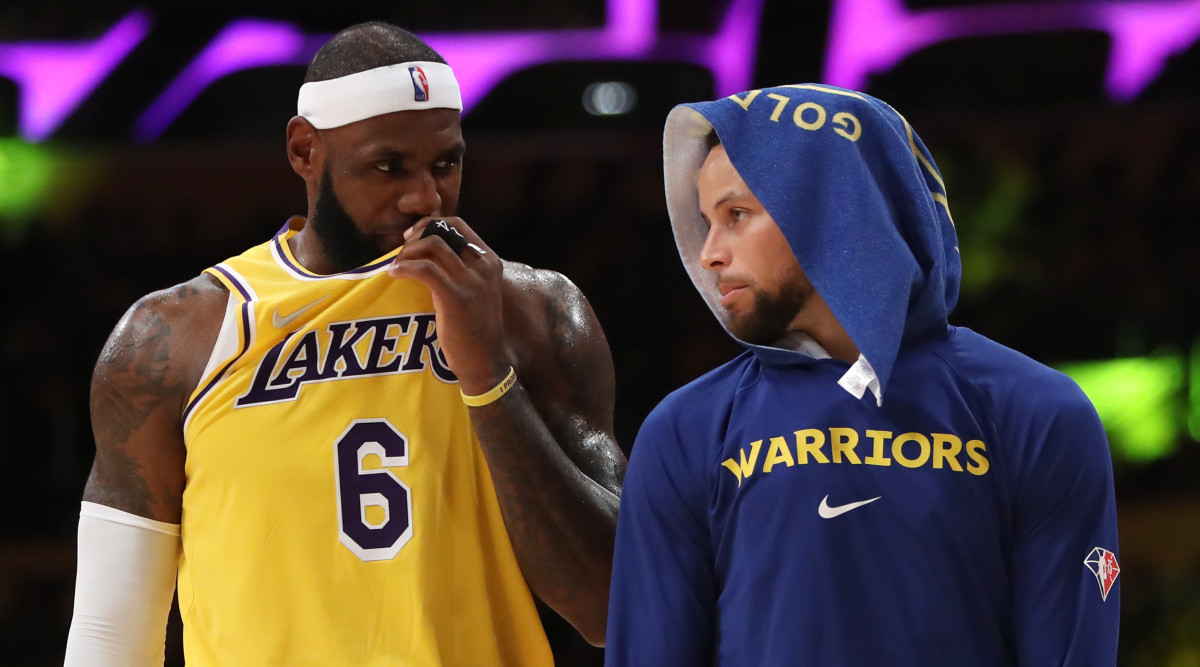 Lakers forward LeBron James and Warriors guard Steph Curry talk to each other during a break in action