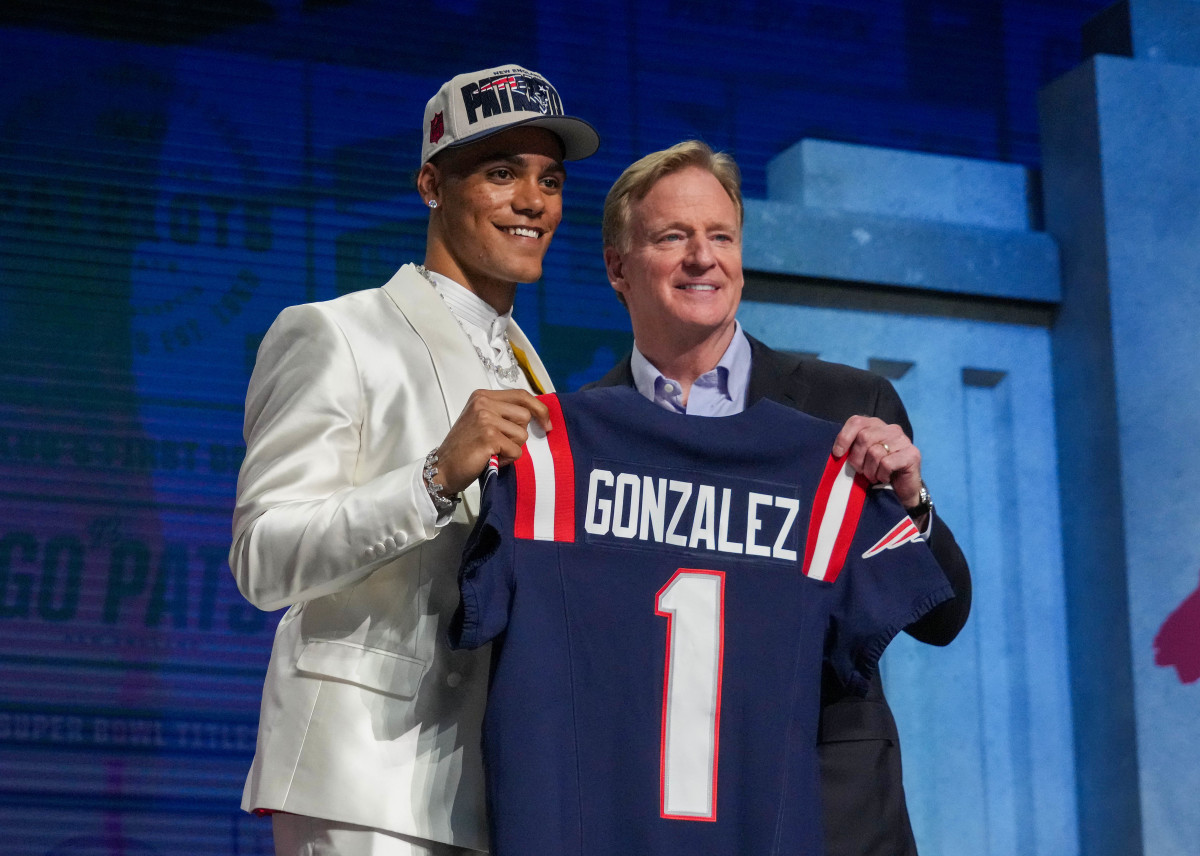 Former Oregon cornerback Christian Gonzalez stands holding a Patriots jersey with NFL commissioner Roger Goodell