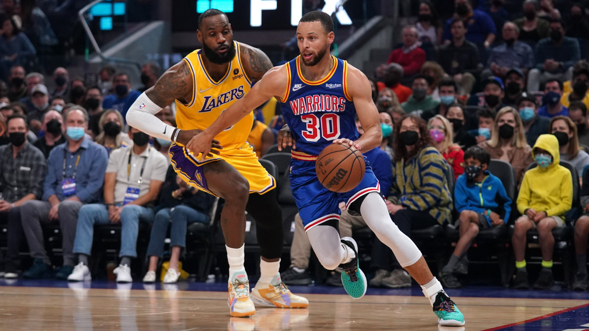 Golden State Warriors guard Stephen Curry dribbles past Los Angeles Lakers forward LeBron James.
