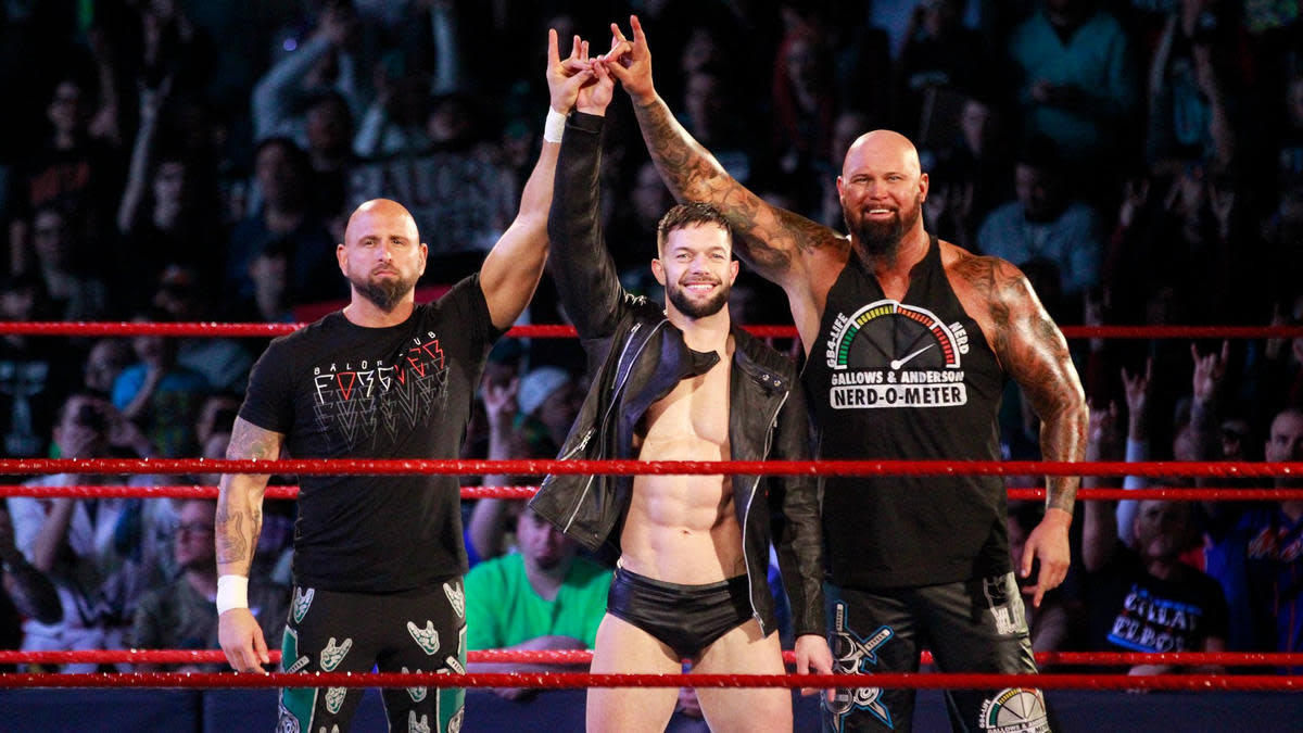 Finn Balor, Karl Anderson and Luke Gallows perform the "too sweet" gesture in a WWE ring