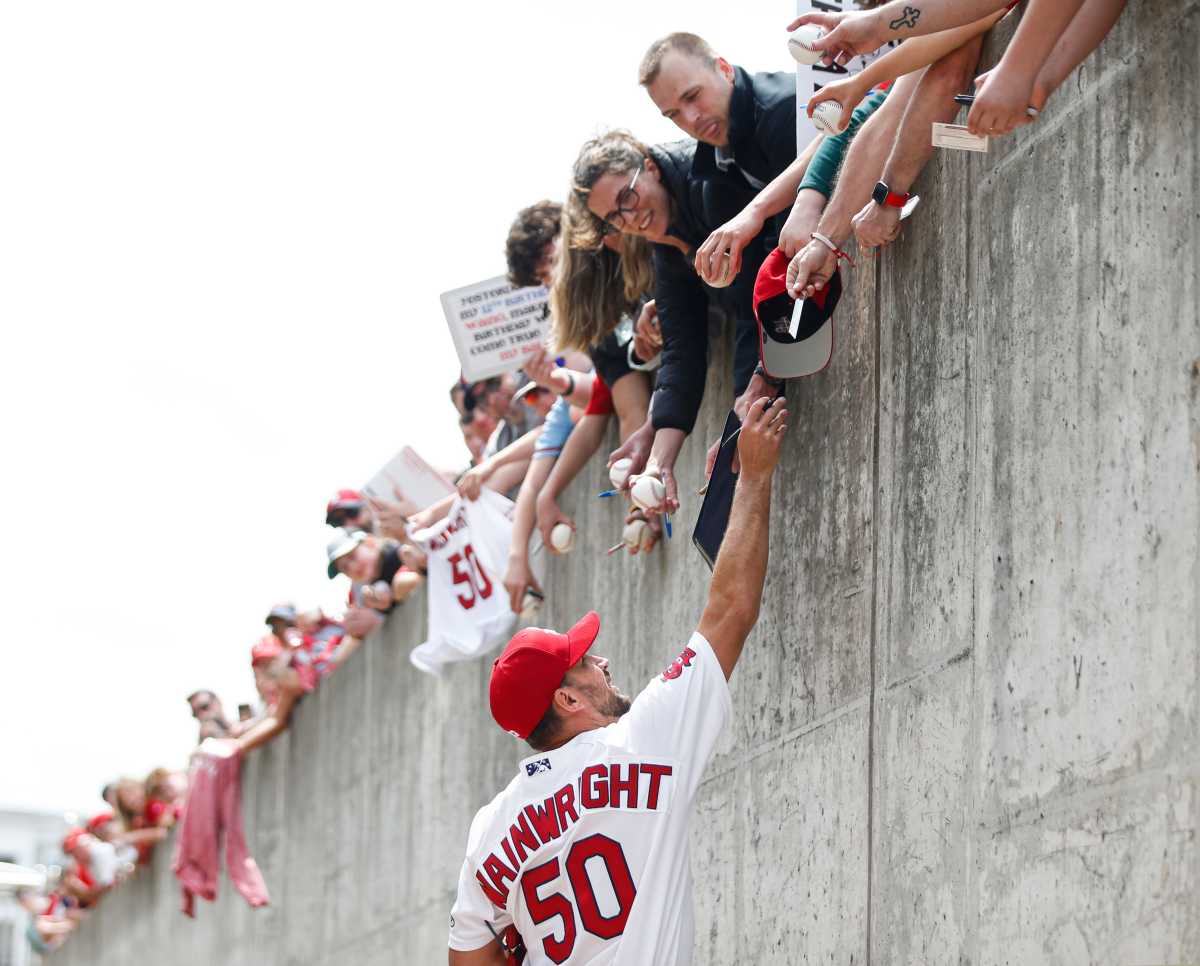 St. Louis Cardinals pitcher Adam Wainwright reaches up to grab a pen and signs autographs for fans