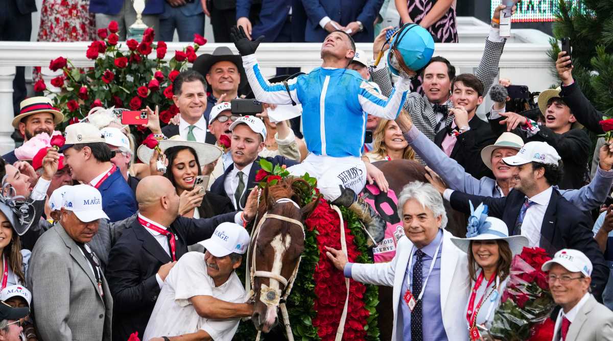 Jockey Javier Castellano celebrates aboard Mage in the Winner's Circle as trainer Gustavo Delgado Sr. puts a hand on the garland of roses after the 149th Kentucky Derby