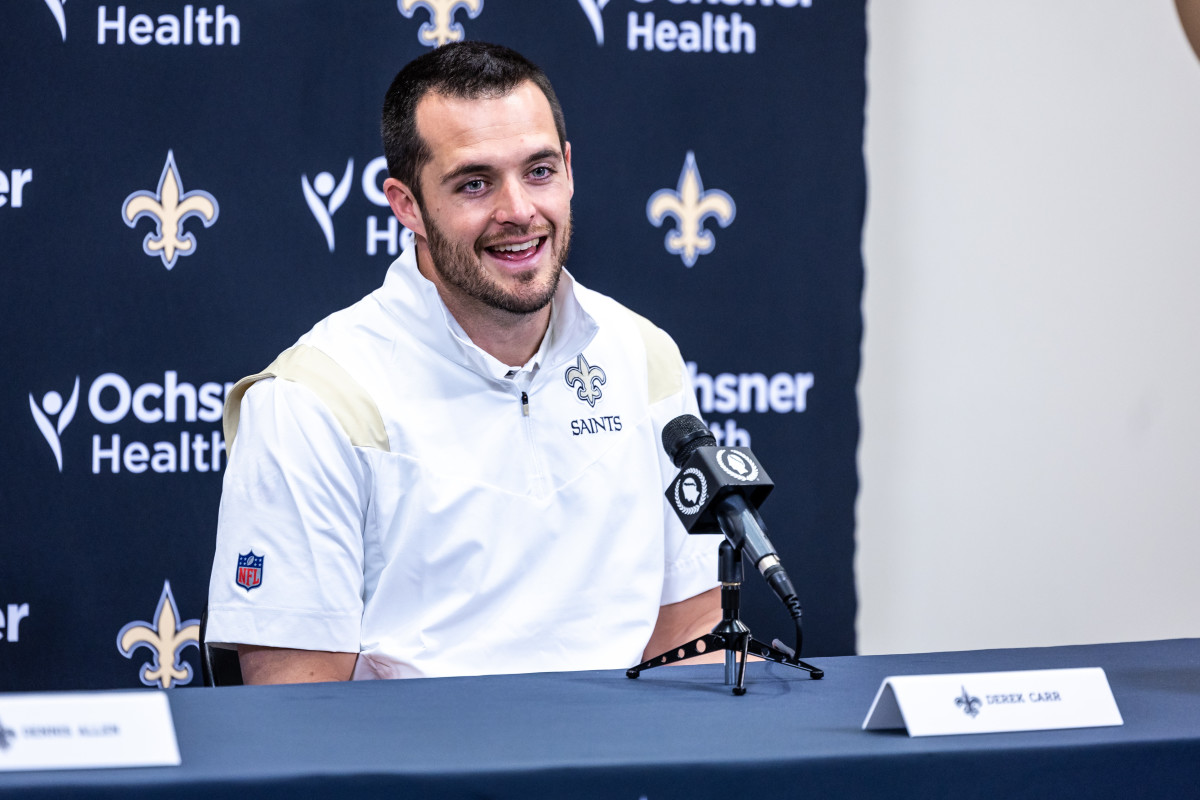 New Orleans Saints quarterback Derek Carr speaks into a microphone sitting at a press conference