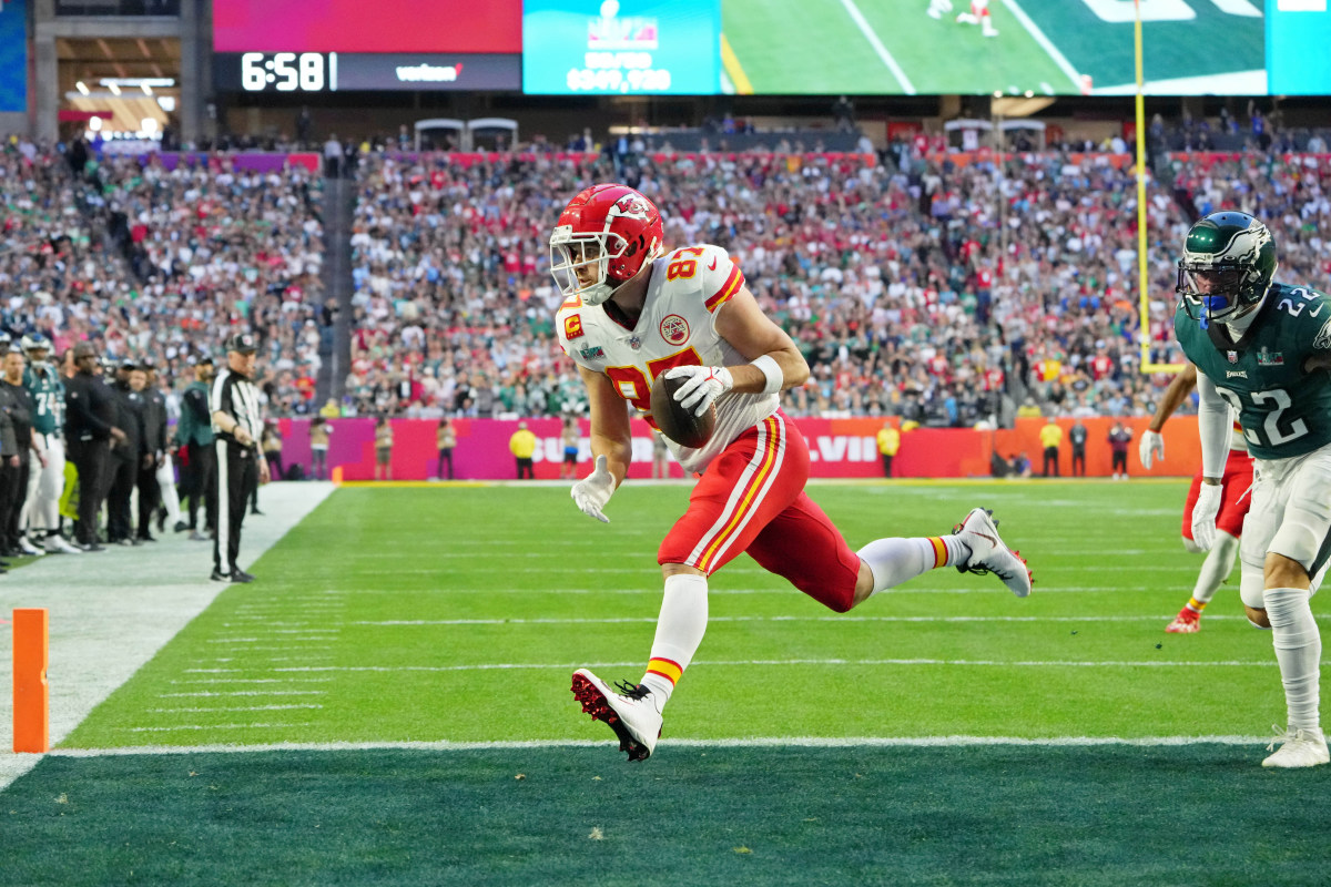 Kansas City Chiefs tight end Travis Kelce runs into the endzone holding the ball in one hand as an Eagles defender trails behind him in the corner of the photo