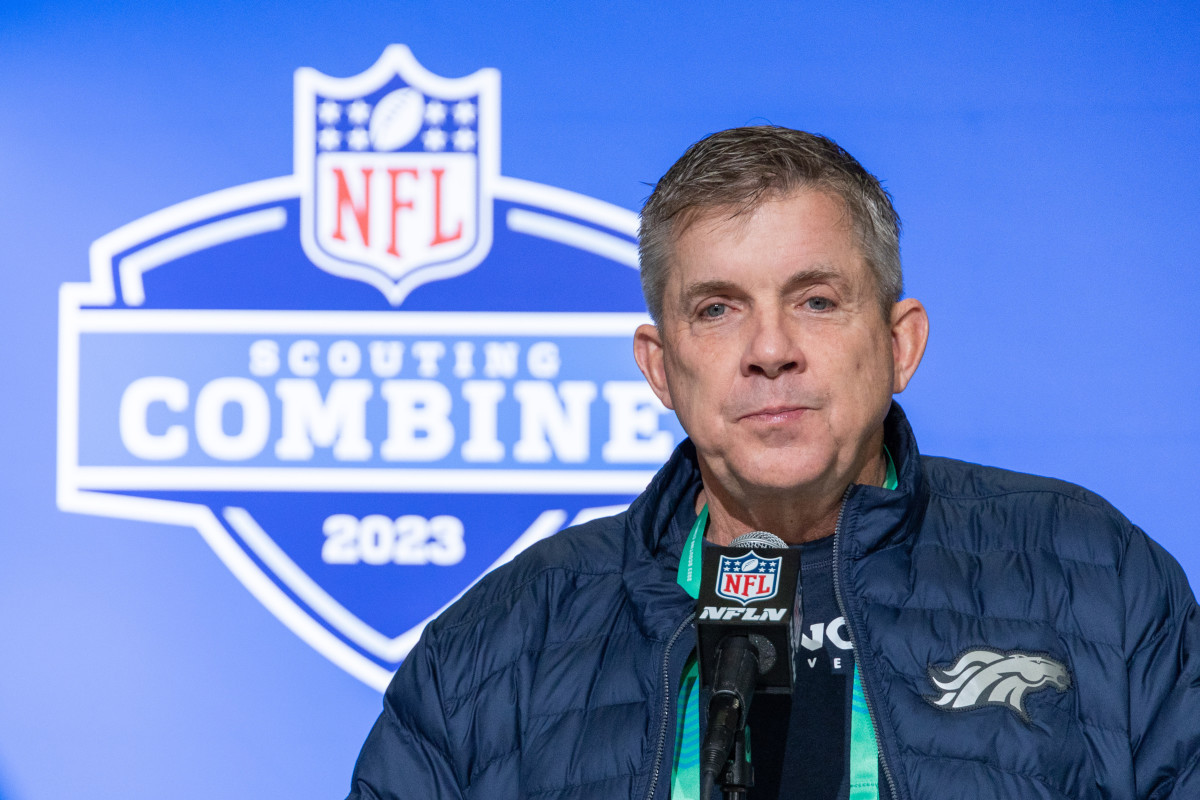 Denver Broncos coach Sean Payton speaks into a microphone with the NFL scouting combine logo behind him