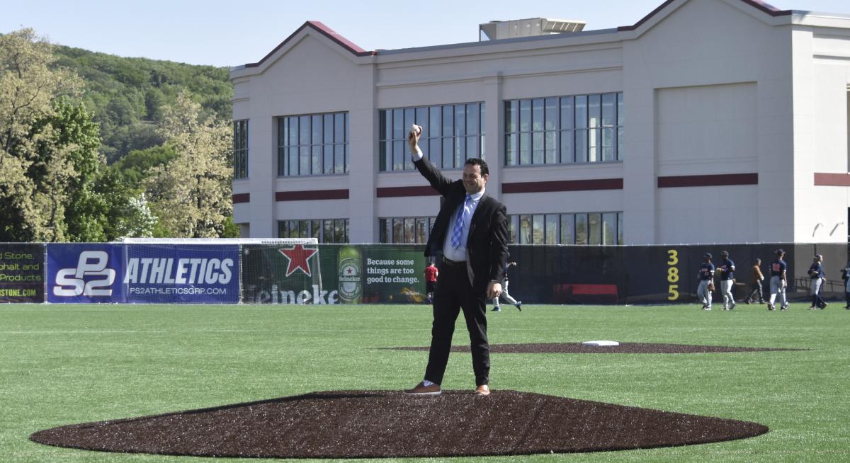 Paterson Mayor Andre Sayegh throws out a ceremonial first pitch ahead of a high school baseball game.