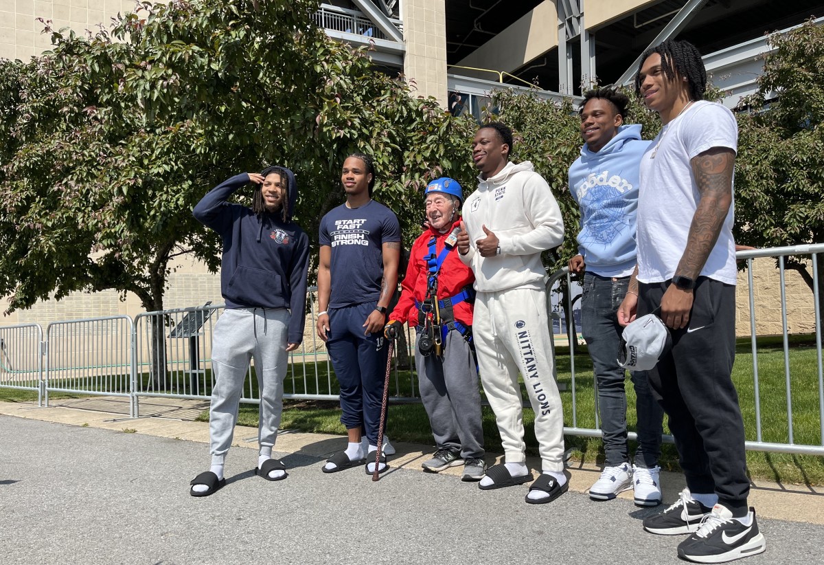 State College resident George Etzweiler, 103, poses with Penn State football players after rappelling Beaver Stadium.