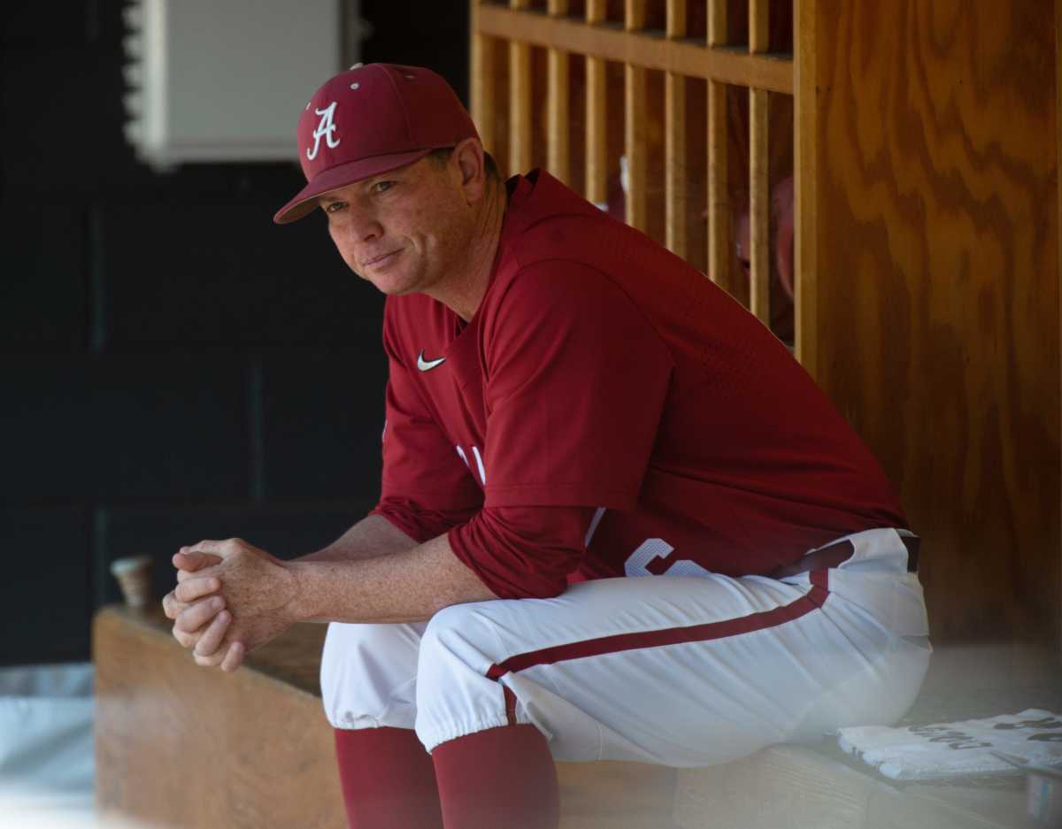 Alabama head coach Brad Bohannon sits on the bench bent over with his arms resting on his legs
