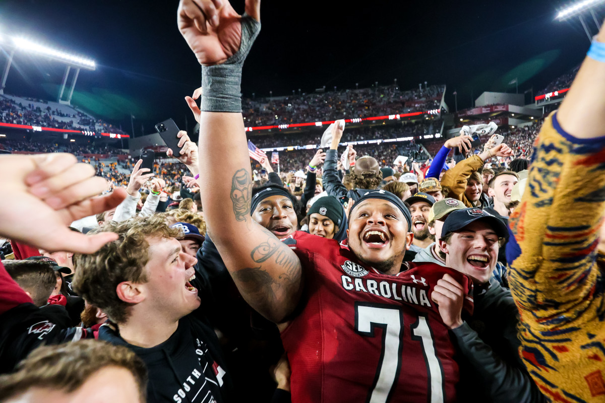 South Carolina Gamecocks offensive lineman Eric Douglas points one hand to the sky while being surrounded by USC students on the field