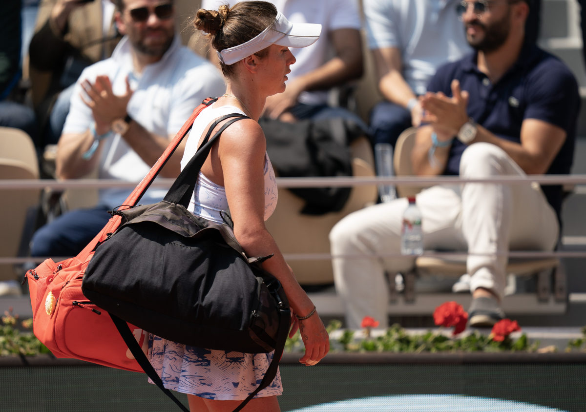 Elina Svitolina holds two bags over her shoulder as she leaves the court