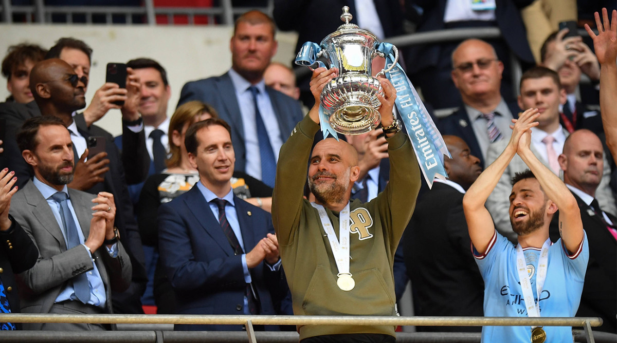 Pep Guardiola lifts Manchester City’s 2023 FA Cup trophy after defeating Manchester United.