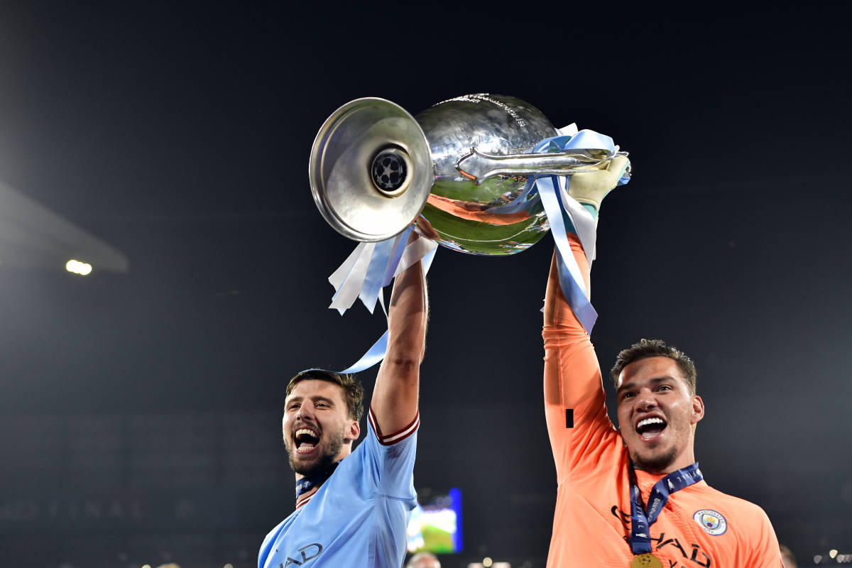 Manchester City teammates Ruben Dias (left) and Ederson pictured lifting the UEFA Champions League trophy together after the 2023 final in Turkey