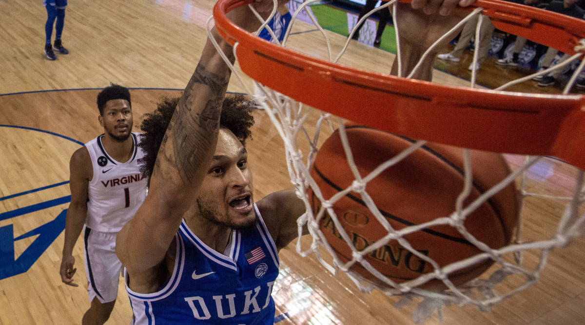 A close-up of Duke center Dereck Lively II dunking, with a Virginia guard looking on in the background