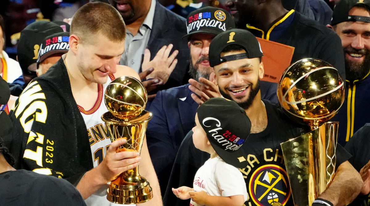 Nuggets stars Nikola Jokić and Jamal Murray stand on the podium to celebrate after winning the 2023 NBA championship.