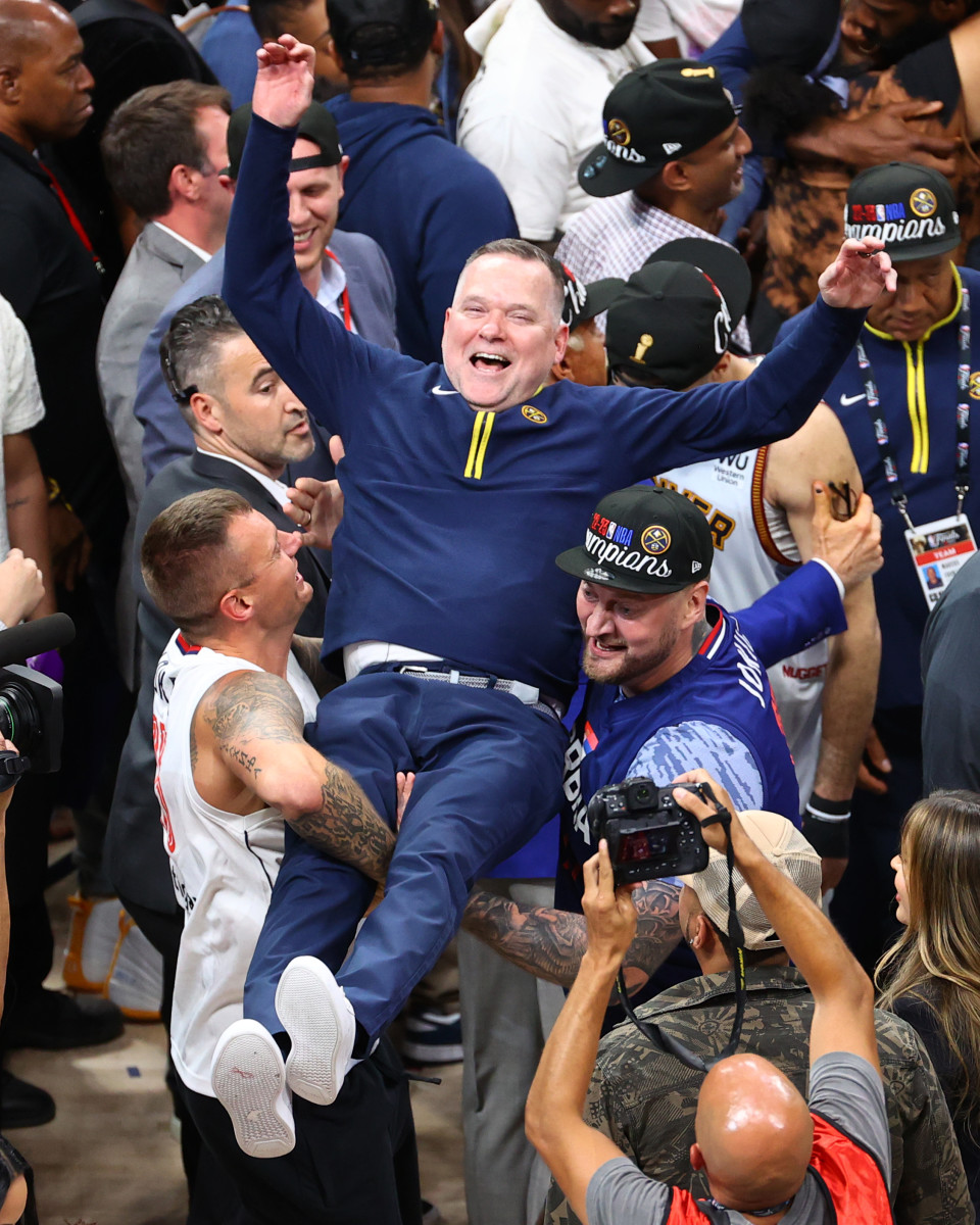 Nuggets coach Michael Malone is hoisted in the air by Nikola Jokić’s brothers, Nemanja and Strahinja.