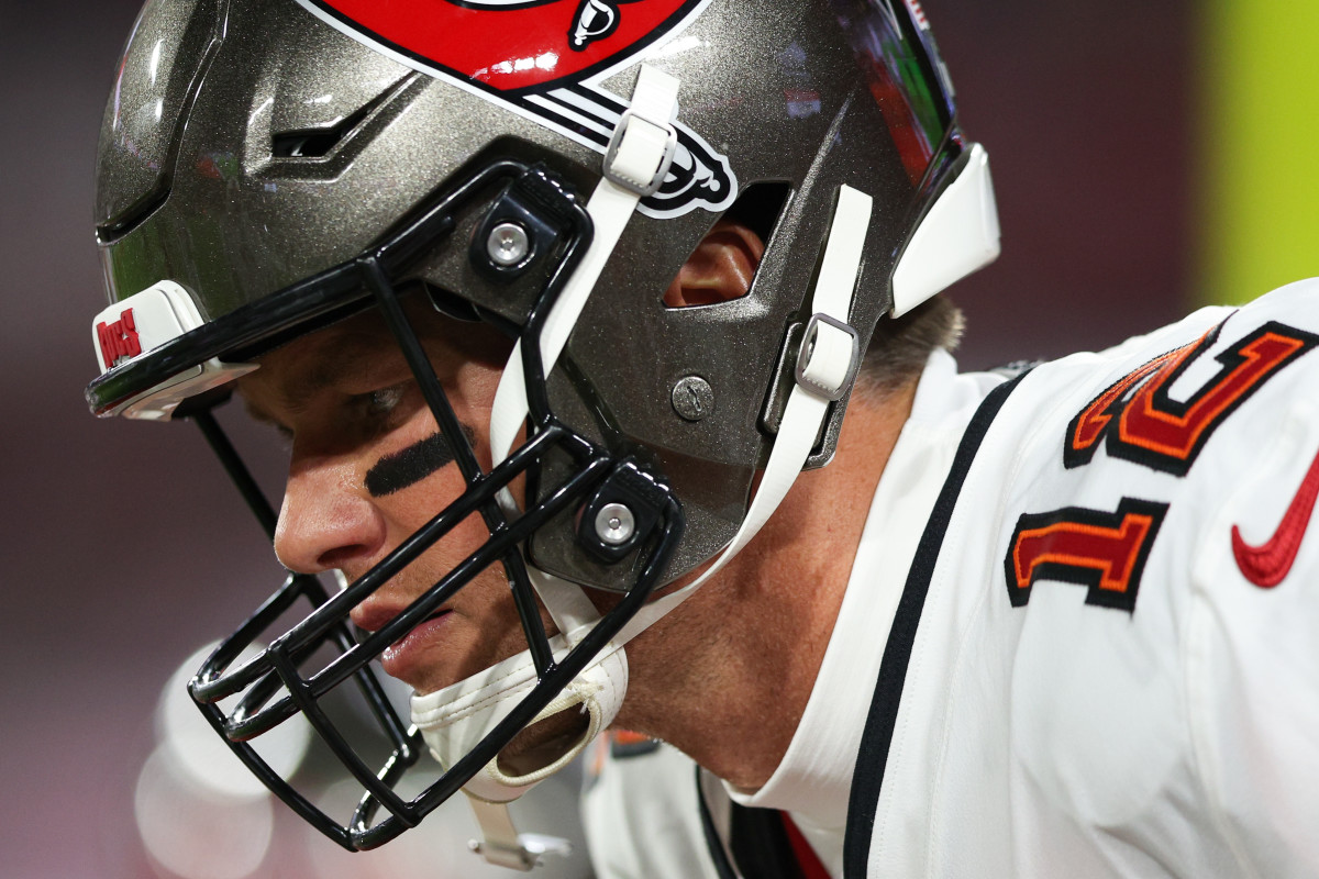 Tom Brady looks down with his helmet on