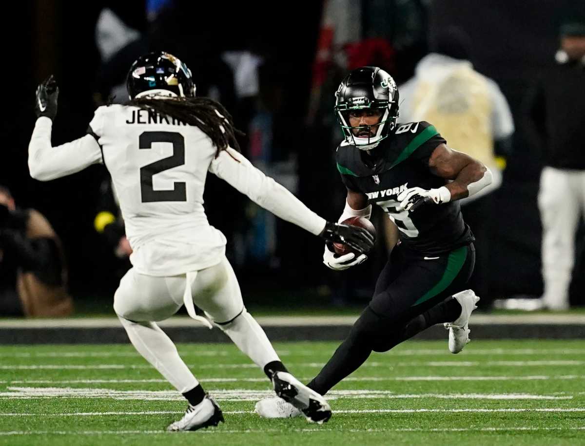 New York Jets wide receiver Elijah Moore (8) runs with the ball with pressure from Jacksonville Jaguars safety Rayshawn Jenkins