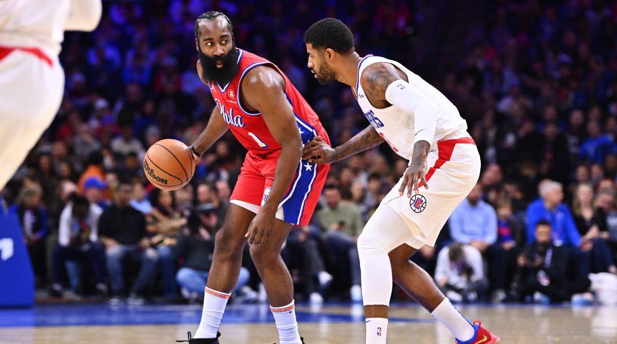 76ers guard James Harden shields the ball from Clippers forward Paul George.