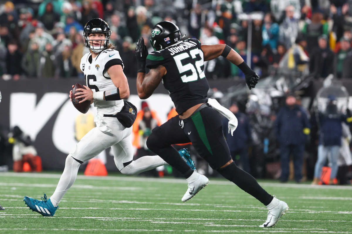 Jacksonville Jaguars quarterback Trevor Lawrence looks to pass while being pursued by New York Jets defensive end Jermaine Johnson