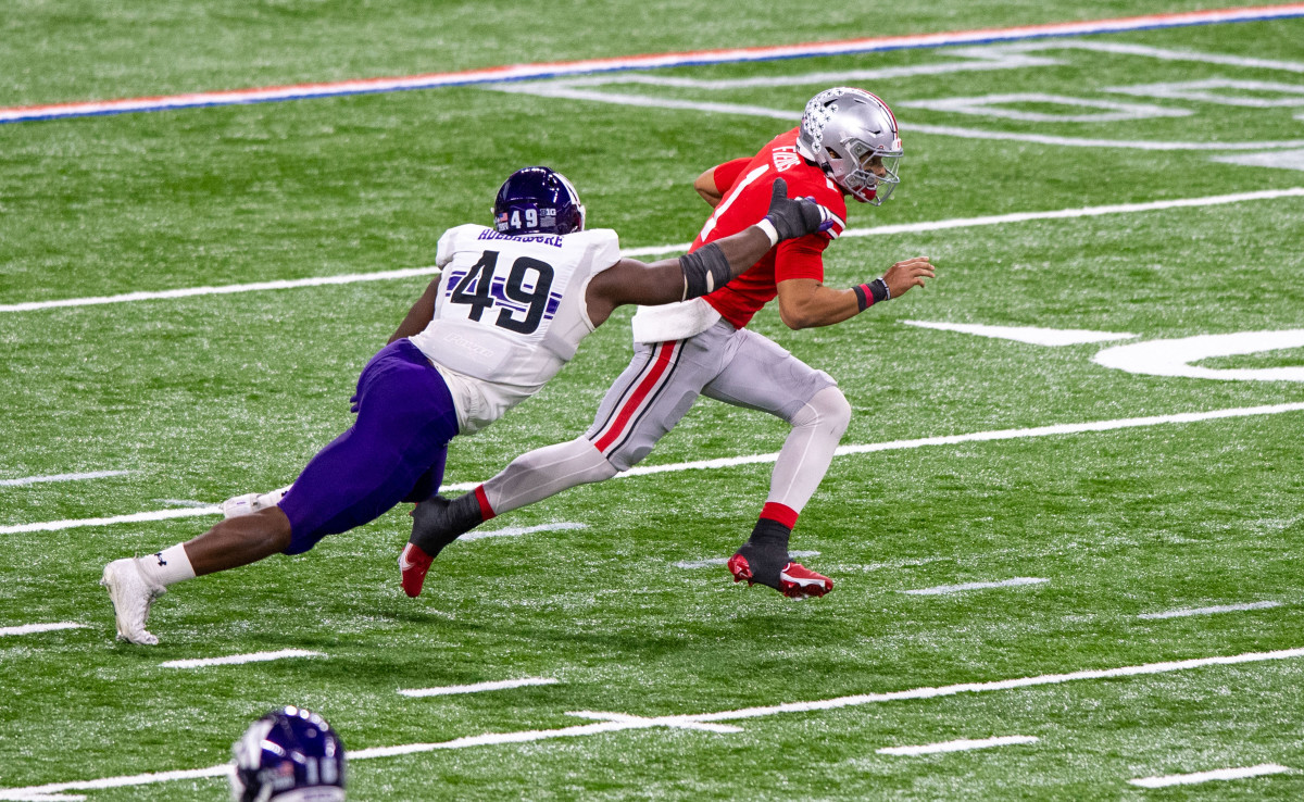 Dec 19, 2020; Indianapolis, Indiana, USA; Northwestern Wildcats defensive lineman Adetomiwa Adebawore (49) reaches out to grab Ohio State Buckeyes quarterback Justin Fields (1) during the first half of the Big Ten Championship game at Lucas Oil Stadium. Mandatory Credit: Doug McSchooler (FLO)-USA TODAY Sports