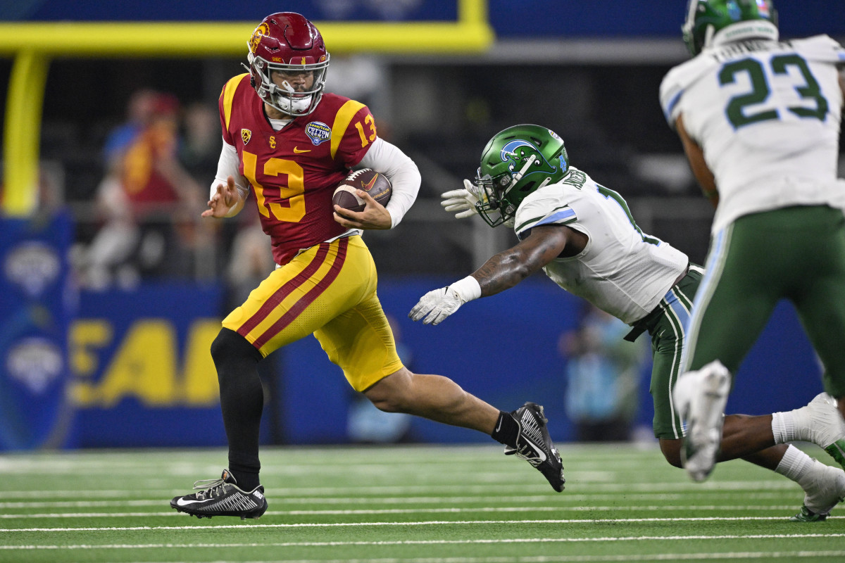 Caleb Williams runs with the ball as a Tulane defender reaches for him