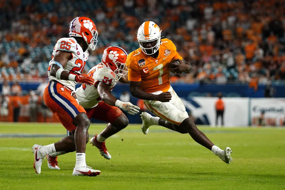 quarterback Joe Milton III runs with the ball as two Clemson defenders try to tackle him