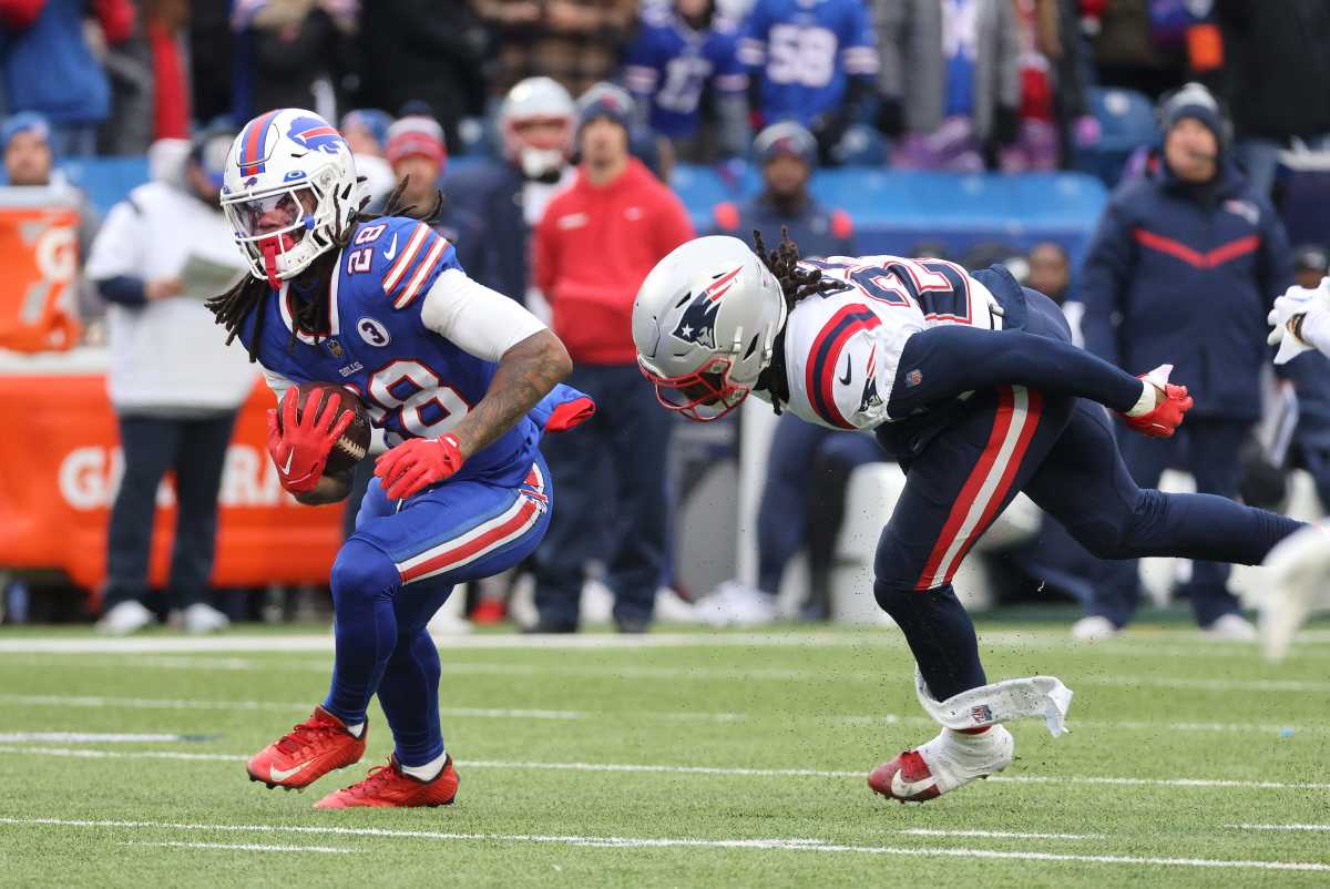 James Cook runs with the ball while a Patriots defender slips as he tries to tackle him