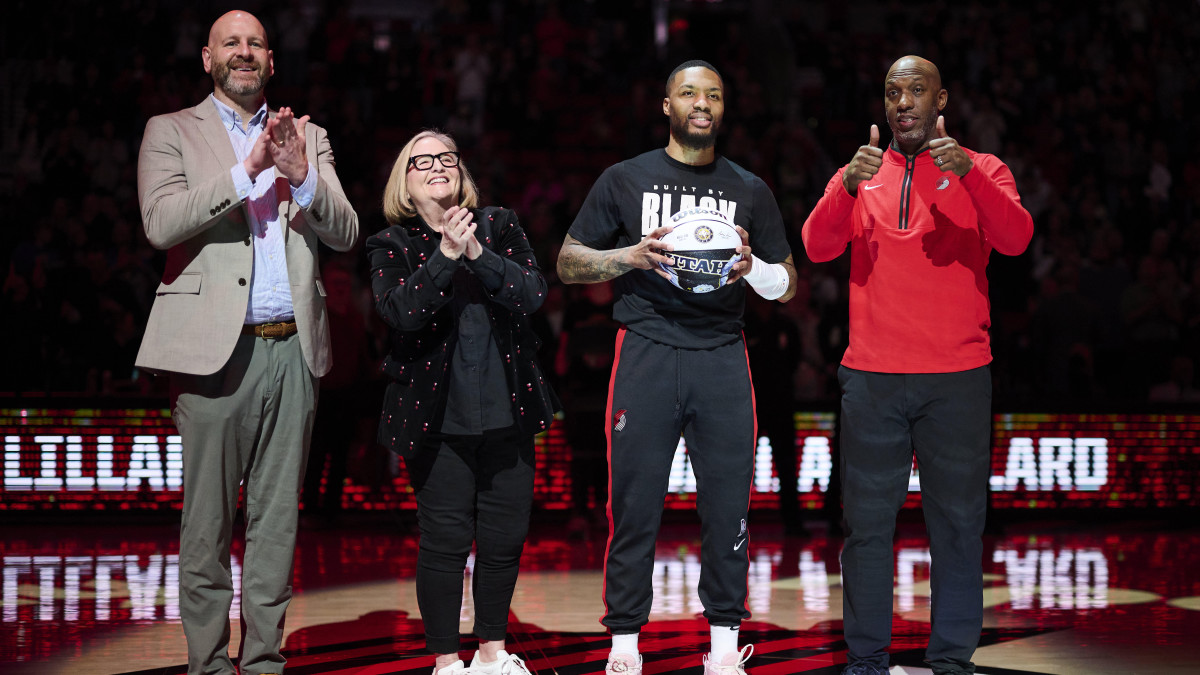 Portland Trail Blazers GM Joe Cronin, left, owner Jody Allen, and head coach Chauncey Billups stand with guard Damian Lillard (0) as he is congratulated on making the NBA All Star team.