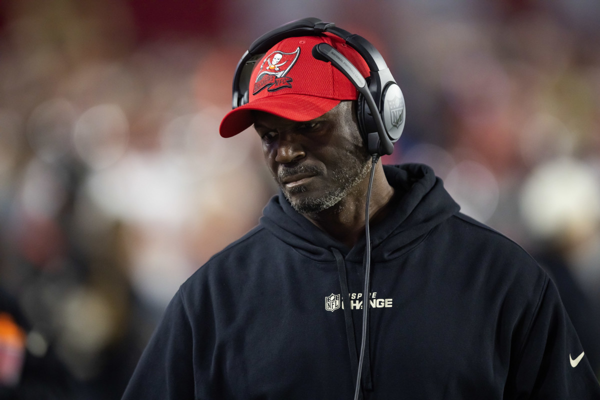 Tampa Bay Buccaneers head coach Todd Bowles looks down wearing a headset and a hat