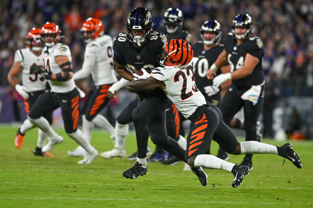 A Ravens player runs with the ball as safety Dax Hill tackles him
