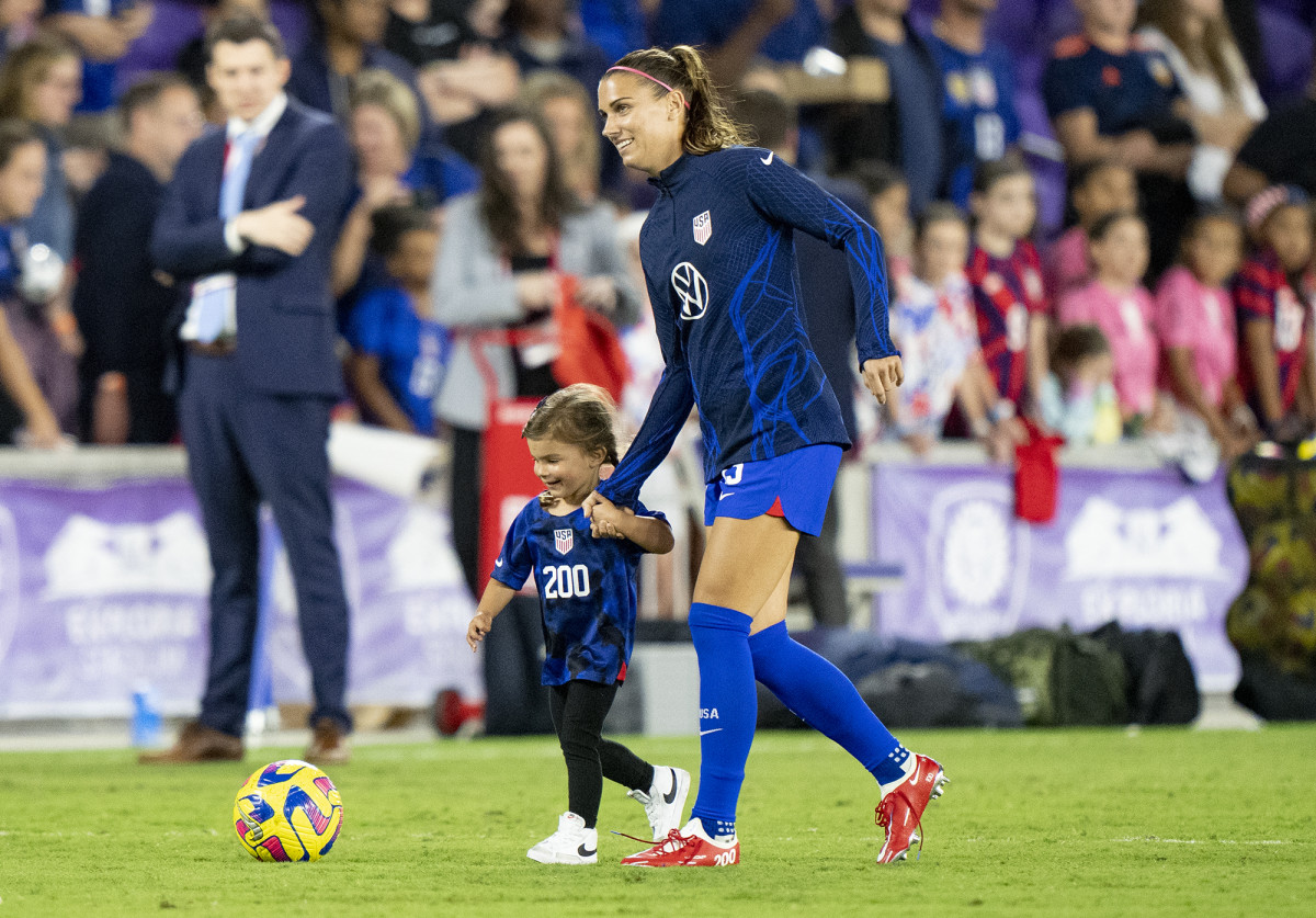 U.S. forward Alex Morgan holds her daughter's hand on the field before a game.