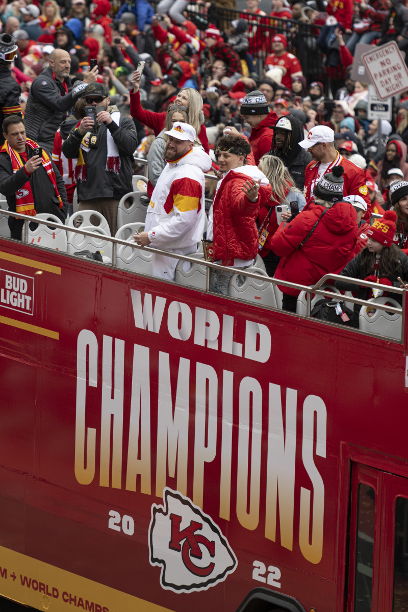 Travis Kelce and Patrick Mahomes ride a bus that says WORLD CHAMPIONS at the Chiefs Super Bowl parade.