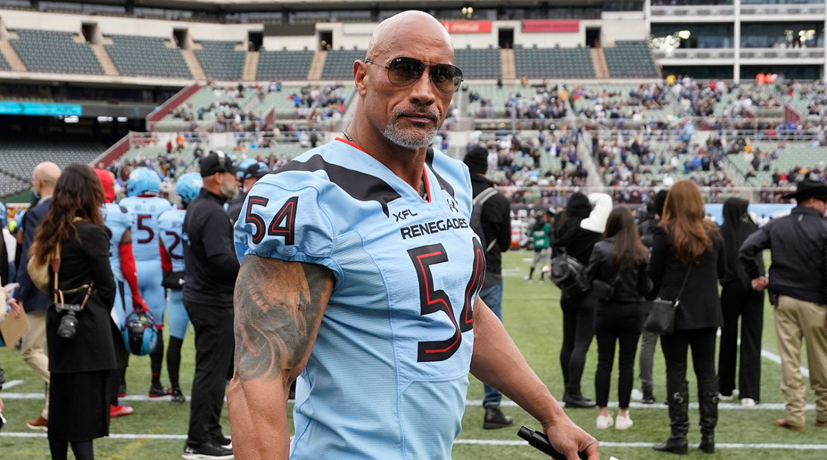 Dwayne Johnson wearing an XFL uniform in a stadium