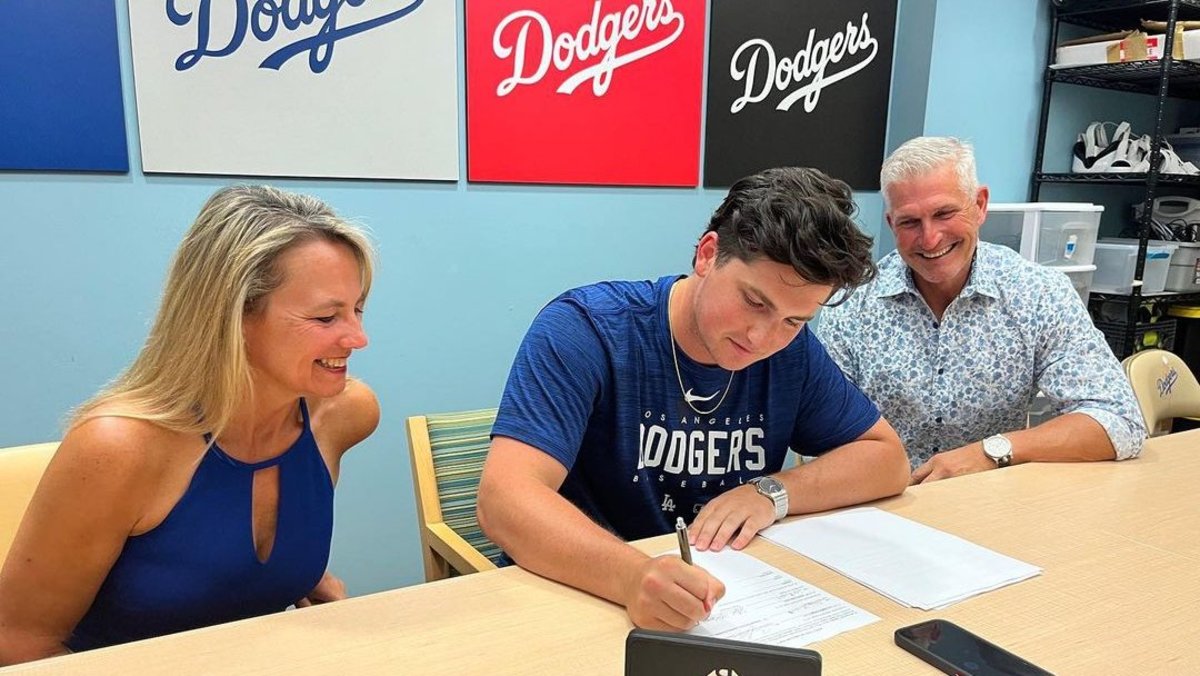 Virginia third baseman Jake Gelof signs his MLB contract with the Los Angeles Dodgers with his parents sitting beside him.