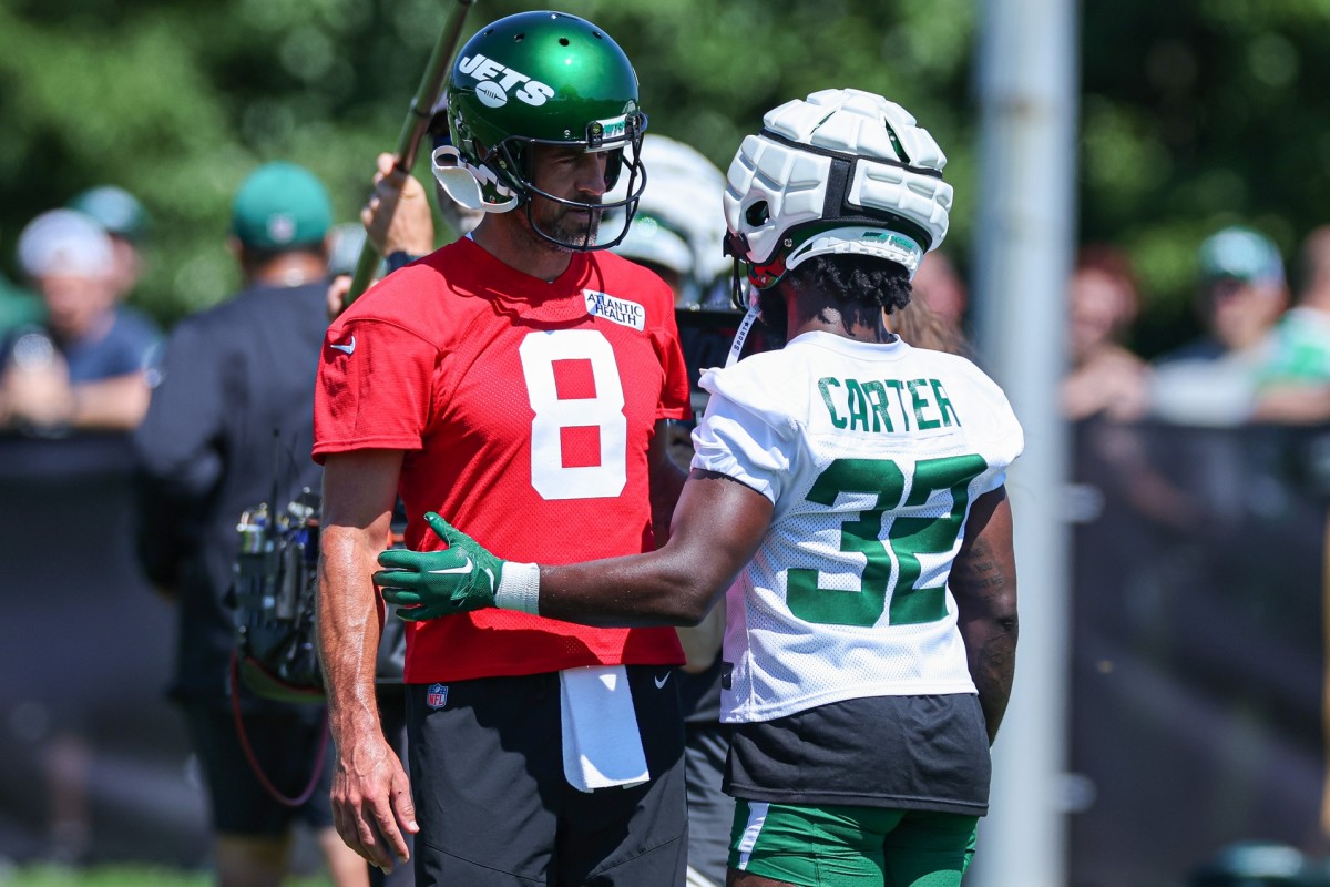 Jets quarterback Aaron Rodgers answers a question from running back Michael Carter during training camp.
