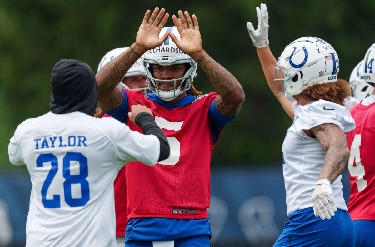 Anthony Richardson high fives his teammate Jonathan Taylor as another Colts player in a helmet runs up to give him one too
